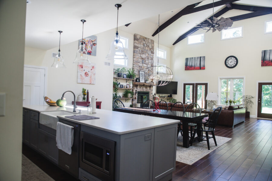 View of the custom designed kitchen into dining room/great room with an enlarged island with a farmhouse apron front sink and built-in microwave. 