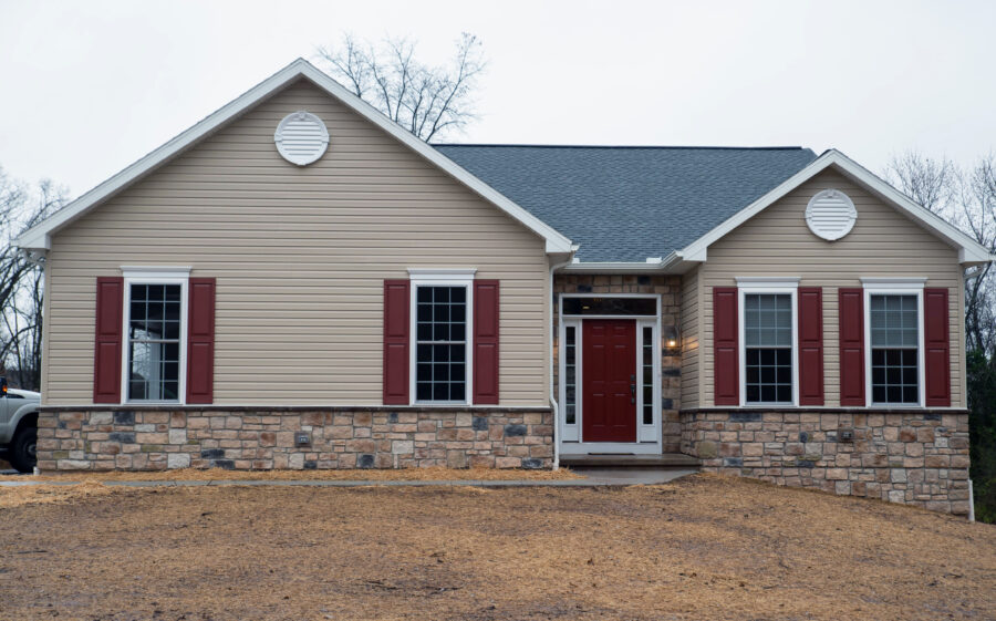The front of a custom-built home in Montgomery County in the country with a neutral color palatte and burgundy shudders and door. 