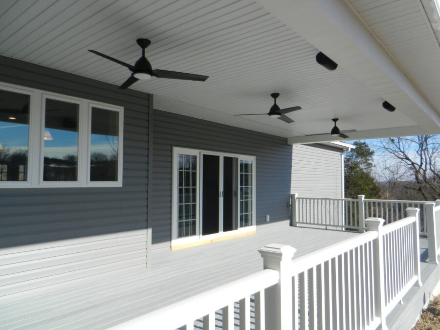 The covered rear deck with vinyl railings and three ceiling fans. 