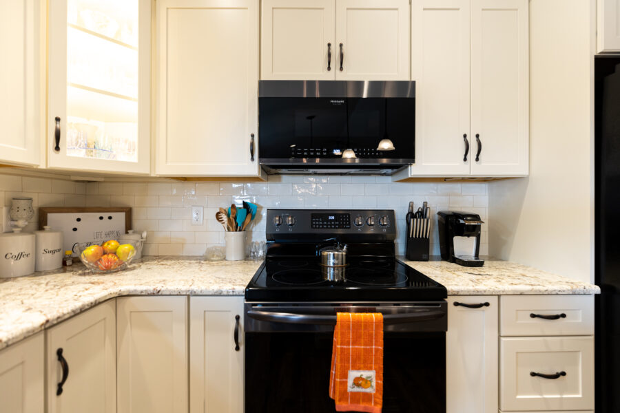 The oven and microwave are surrounded by white cabinets in this kitchen
