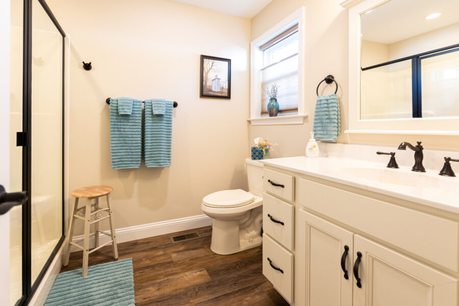 A bathroom with a white vanity, black hardware and blue towels