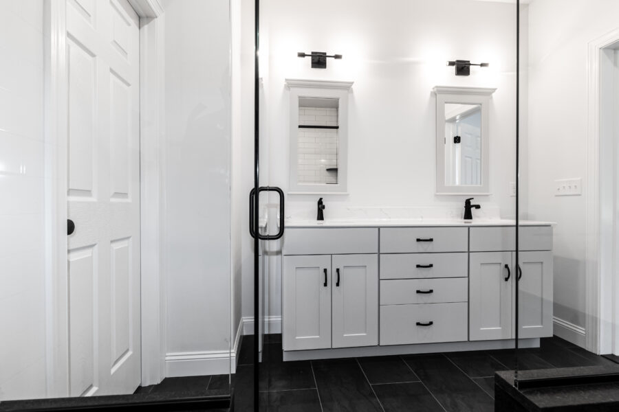An all white bathroom with black floors and accents