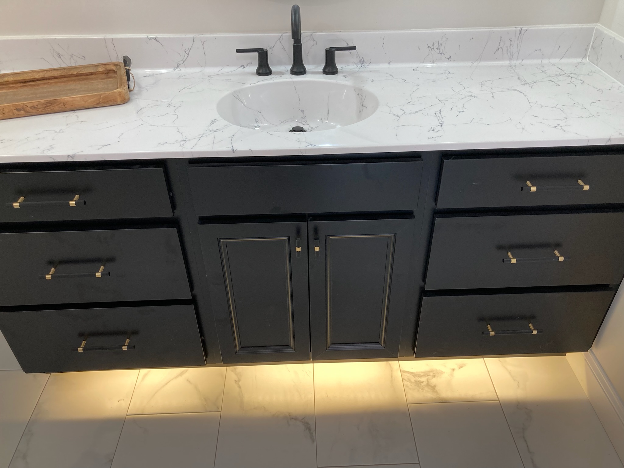 A black bathroom vanity with white countertops and gold accents